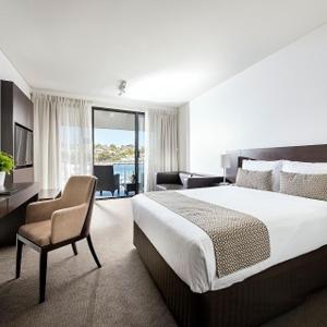 ein Hotelzimmer mit einem großen Bett und einem Stuhl in der Unterkunft Pier 21 Apartment Hotel Fremantle in Fremantle