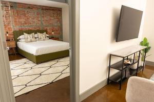 ein Schlafzimmer mit einem Bett und einer Ziegelwand in der Unterkunft Stylish And New 1 Br Loft Apartment Right Downtown in Roanoke