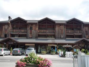 a large building with cars parked in a parking lot at Les Gets - Appart cosy avec mezzanine et parking, proche pistes - FR-1-623-145 in Les Gets