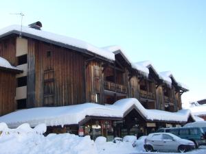 a building covered in snow with cars parked in front at Les Gets - Appart cosy avec mezzanine et parking, proche pistes - FR-1-623-145 in Les Gets +5 photos