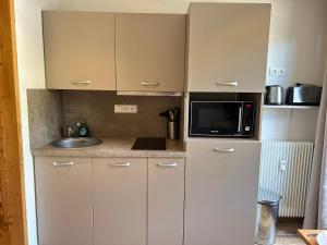 małą kuchnię z białymi szafkami i kuchenką mikrofalową w obiekcie Studio Les Gets, 1 pièce, 4 personnes - FR-1-623-231 w mieście Les Gets