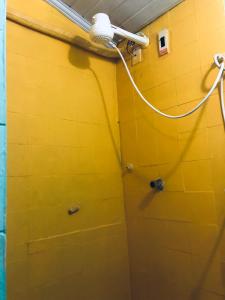 a bathroom with a yellow wall with a shower head at Pousada Biribiri in Salvador