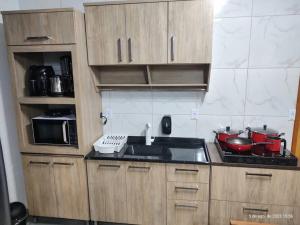 a kitchen with wooden cabinets and a sink and a microwave at CASA CLIMATIZADA COM HIDROMASSAGEM PRÓXIMO BETO CARRERO E PRAIAS - Casa 2 DuMar Hospedagem in Penha +22 photos