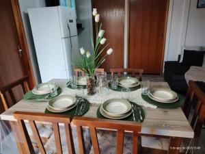 a dining room table with plates and a vase of flowers at CASA CLIMATIZADA COM HIDROMASSAGEM PRÓXIMO BETO CARRERO E PRAIAS - Casa 2 DuMar Hospedagem in Penha