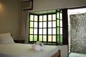 a bedroom with two beds and a window with towels at Pousada Casa da Pedra in Búzios