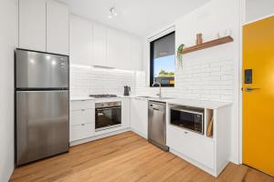 a kitchen with white cabinets and a stainless steel refrigerator at Peppertree Apartments in Sale