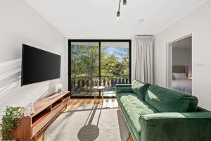 a living room with a green couch and a flat screen tv at Peppertree Apartments in Sale