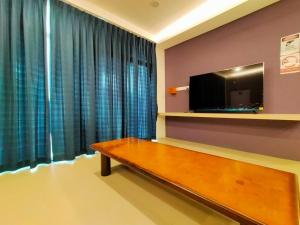 a living room with a wooden bench and a flat screen tv at Agape Hostel in Sibu