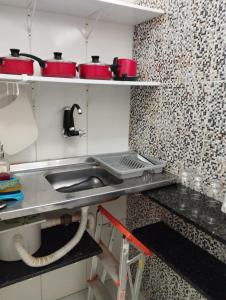 eine Küche mit einer Spüle und roten Töpfen und Pfannen in der Unterkunft Kit Nets D+ in Baixio