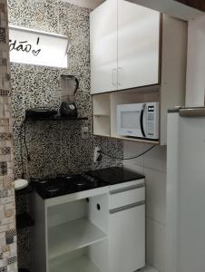 eine Küche mit weißen Schränken und einer Mikrowelle in der Unterkunft Kit Nets D+ in Baixio