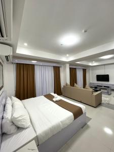 a bedroom with a large bed and a couch at Staycation Hotel in San Jose