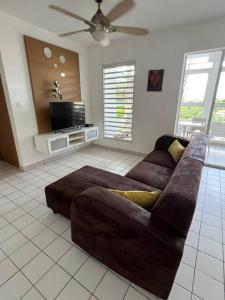sala de estar con sofá marrón y TV en Appartement F4 Petit bourg, en Petit-Bourg