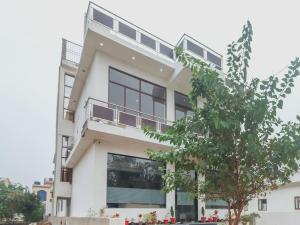 a white building with a tree in front of it at Super OYO Taj Classic in Tājganj