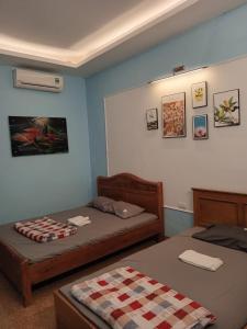 Un dormitorio con 2 camas y una pared con cuadros. en Nhà nghỉ Thành Trung, 
