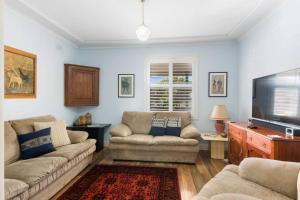 a living room with two couches and a flat screen tv at Ocean Blue Escape - Beachside Living & Granny Flat in Wollongong