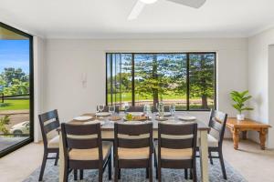 a dining room with a table and chairs and a large window at Esplanade Escape - Beachfront Family Bliss in Thirroul
