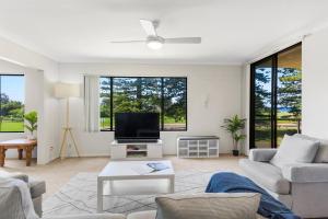 a living room with a couch and a tv at Esplanade Escape - Beachfront Family Bliss in Thirroul
