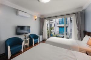 a hotel room with a bed and two chairs and a window at Cheers Hostel Hanoi in Hanoi