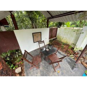 un patio con 2 sillas, una mesa y una foto en The Heritage Villa - Poovar, en Neyyāttinkara