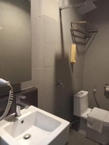 ein Badezimmer mit einem Waschbecken, einem WC und einem Spiegel in der Unterkunft T+ Hotel Sungai Korok in Alor Setar