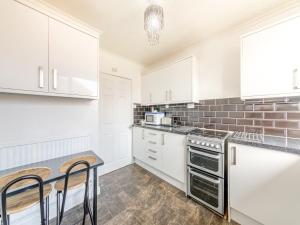 a kitchen with white cabinets and a table and chairs at Westfield in Newbiggin-by-the-Sea