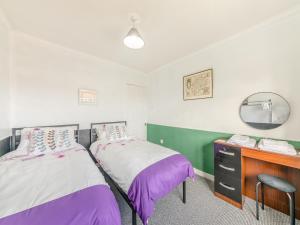 two beds in a room with a vanity and a mirror at Westfield in Newbiggin-by-the-Sea