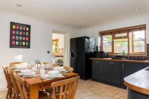 a kitchen with a table with chairs and a refrigerator at Modern 4 Bed Detached Private House-Parking-Garden in Down Hatherley