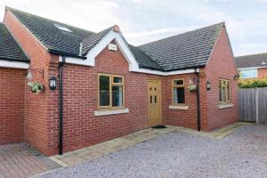 a red brick house with a yellow door at Modern 4 Bed Detached Private House-Parking-Garden in Down Hatherley