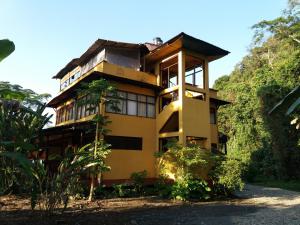 a yellow house on a hill with trees at Paraiso Pilcopata Inn in Pillcopata