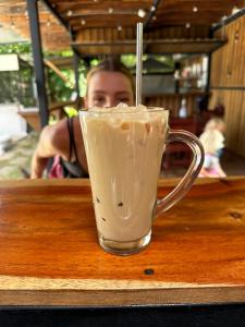 Ein Mann sitzt an einem Tisch mit einem Drink in einer Tasse. in der Unterkunft Pipa House Samara in Sámara