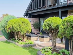 a garden with trees and benches in front of a building at Holiday home Förslöv in Förslöv