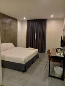 ein Hotelzimmer mit einem Bett, einem Schreibtisch und einem Tisch in der Unterkunft T+ Hotel Sungai Korok in Alor Setar