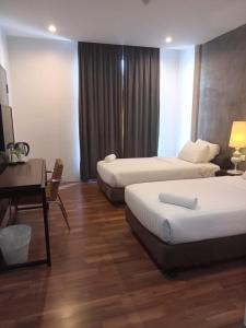 a hotel room with two beds and a desk at T+ Hotel Sungai Korok in Alor Setar