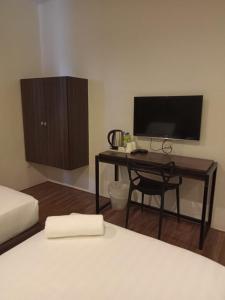 Schlafzimmer mit einem Schreibtisch, einem TV und einem Bett in der Unterkunft T+ Hotel Sungai Korok in Alor Setar