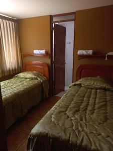 a hotel room with two beds and a door at Hotel La Villa in Arequipa