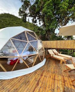 an igloo on a deck with chairs and an umbrella at MACA GLAMPING in Calima