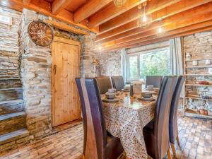 comedor con mesa, sillas y pared de piedra en Bwlch Farm Lodge, en Briton Ferry