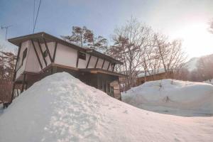 une pile de neige devant une maison dans l'établissement Hakuba Hoshikage - beautiful mountain cottage, à Hakuba