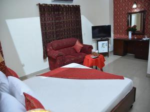 a bedroom with a bed and a couch and a chair at Luxury one hotel Lahore in Lahore