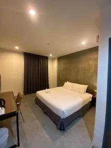 Schlafzimmer mit einem großen weißen Bett und einem Schreibtisch in der Unterkunft T+ Hotel Sungai Korok in Alor Setar