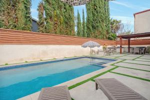 - une piscine avec des chaises et un parasol dans la cour dans l'établissement Beautiful 5 bedroom 8 bed sleeps up to 16 with pool near Universal Studios, à Los Angeles