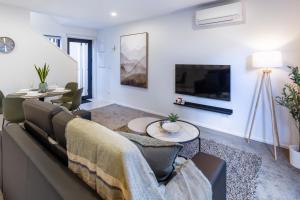 a living room with a couch and a tv at An Easy Walk to the CBD - 2 Bed, 2 Bathroom in Christchurch