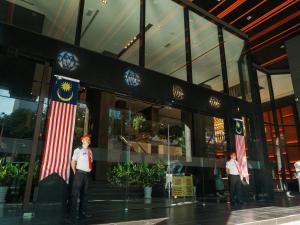 a man standing in front of a building with an american flag at Stay Collection Bukit Bintang in Kuala Lumpur