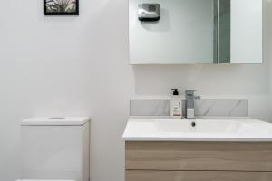a white bathroom with a sink and a mirror at An Easy Walk to the CBD - 2 Bed, 2 Bathroom in Christchurch +19 photos