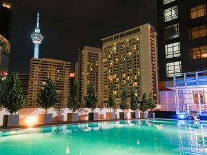 uma grande piscina com um horizonte da cidade à noite em Stay Collection Bukit Bintang em Kuala Lumpur