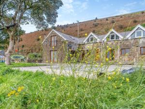 a stone house with a hill in the background at Bwlch Farm Lodge in Briton Ferry