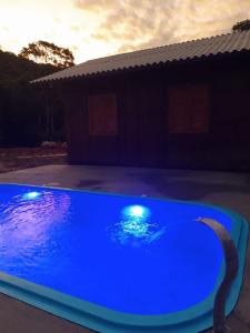 einem blauen Pool mit Lichtern vor einem Haus in der Unterkunft Chácara Monte Cristo in Aguas Mornas
