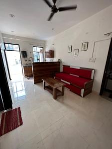 a living room with a red couch and a table at Lalita Kunj - Fully furnished Appartment Vrindavan in Vrindāvan