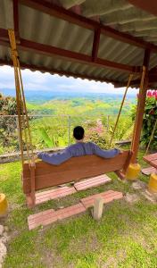 un hombre sentado en un columpio con una vista en Eco Hotel La Selecta Campestre, en Pereira