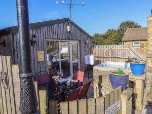 a black shed with a fence and a hot tub at The Old Hen Shed in Ingrow
